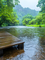 Wall Mural - A serene river flows beside a wooden dock under misty mountains for relaxation