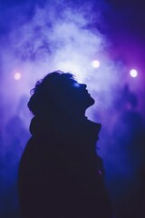 Wall Mural - silhouetted person gazing upwards in smoky purple and blue light.