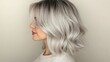 © boy 3344 - Side view of a woman with silver-gray hair styled in a layered shag cut, with soft waves adding volume and texture, standing against a neutral beige backdrop.
