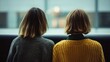 © VK Studio - Two people with identical haircuts sit closely, gazing outside, sharing a quiet, introspective moment of connection and reflection.
