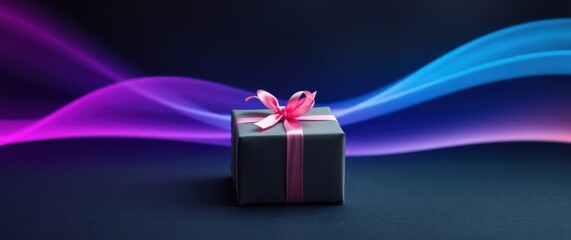 Wall Mural - Wrapped gift with pink ribbon on dark surface against blurred wavy light trails of purple and blue color.