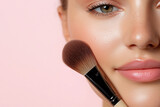 Zbliżenie twarzy kobiety z brokatowym makijażem i pędzlem na jasnoróżowym tle