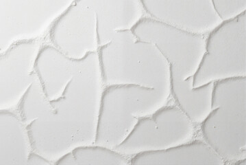 White textured surface with cracked and rippled patterns, creating a minimalist and abstract composition.