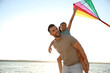 © New Africa - Happy father and his child playing with kite near sea. Spending time in nature