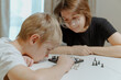 © looking2thesky - A loving mother and her son play chess together in a cozy home setting. The boy, wearing a hearing aid, focuses on the game with excitement. A heartwarming moment of parenting, bonding, and childhood