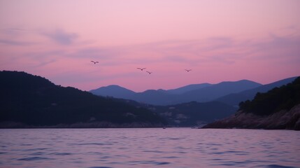 Wall Mural - a serene sunset view over mountains and calm waters with birds flying in the sky.
