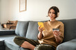 © Stock 4 You - Young freelance woman using cellphone smartphone paying app and credit debit card for online shopping sitting at home on sofa. Latin girl freelancer adult female student doing money transfer by phone