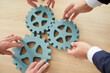 © Studio Romantic - Close up shot of a business people hands connecting cog wheels or gears on a table. Partnership, teamwork, and collaboration within the team. Group engaged in problem solving or finding solution.