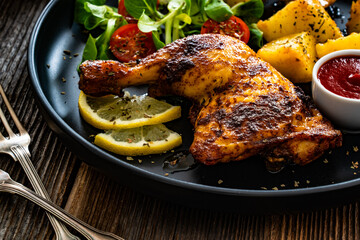 Wall Mural - Oven roasted chicken thigh with potatoes and fresh salad on wooden table	