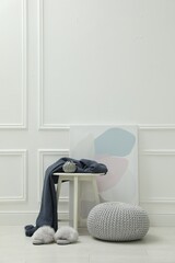 Wall Mural - Knitted pouf, fuzzy slippers and decor elements near white wall indoors. Space for text