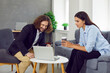 © Studio Romantic - Two people meeting in office and discussing business deal. Happy young man and woman sitting on chair and couch by small table, talking about work and looking at laptop computer