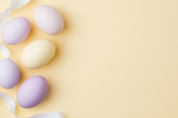 Wall Mural - five pastel colored easter eggs arranged on a beige background with a white ribbon, creating a simpl