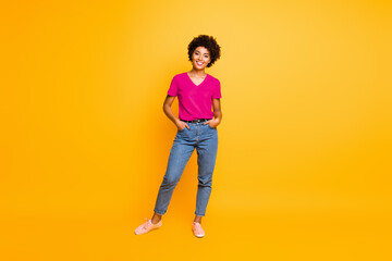 Wall Mural - Full length body size photo of cool swag good black millennial girl posing in front of camera showing her coolness wearing jeans denim sneakers isolated over vibrant color background