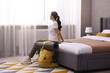 © New Africa - Traveller with backpack sitting on bed in hotel room