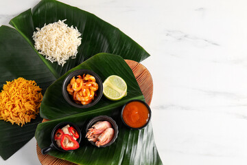 Canvas Print - Cut banana leaves with different food and sauce on white marble table, flat lay. Space for text