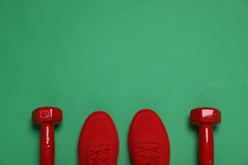 Wall Mural - Sports equipment. Dumbbells and sneakers on green background, flat lay. Space for text