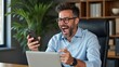 © Ada - Middle-aged Latin or indian businessman screaming proud cheering with excitement , man read great news on smartphone celebrating victory and success sitting front of laptop computer working at office