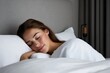© jureephorn - Restful woman sleeping comfortably on a large bed, dim warm lighting adding depth to the peaceful setting, modern interior design with a minimalist touch, high-resolution clarity