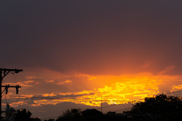 Wall Mural - sunset over the city with orange sky and silhouette of electric pole