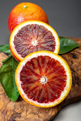 Wall Mural - Sicilian sweet juicy yellow and red blood oranges with green leaves close-up