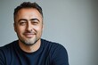 © Pixel Mind - Smiling man with short hair wearing a dark sweater against a gray background
