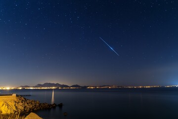 Wall Mural - Star is shooting across the sky above a body of water
