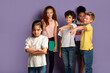 © Prostock-studio - Stop bullying in schools. Upset Asian girl and her cruel classmates pointing at her over lilac background