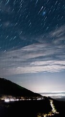 Wall Mural - night sky stars with silhouette of mountain and glowing city bellow