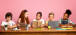 © Prostock-studio - School time. Multiethnic kids with different gadgets and books sitting at table against pink background, empty space. Panorama