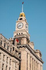 Wall Mural - Clock tower of historic building in Shanghai against a clear blue sky.