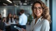 © liliyabatyrova - A confident business leader with a bright smile holds a tablet while surrounded by colleagues in a contemporary office. The atmosphere is collaborative and inspiring, showcasing teamwork