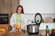 © Pixel-Shot - Young woman with multi cooker cutting zucchini at table in kitchen