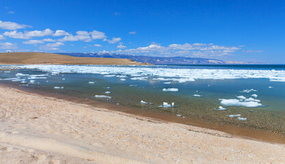 Wall Mural - Baikal Lake in sunny May day. Sandy beach of Olkhon Island.  White ice floats floating on blue water of the shallow Elga Bay of Small Sea Strait. Beautiful spring landscape. Natural season background