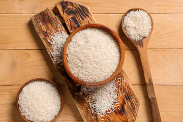 Canvas Print - Bowls with raw rice and spoon on wooden background