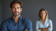 © Wiseman - confident modern businessman in a deep blue shirt with crossed arms standing alone against a neutral gray background