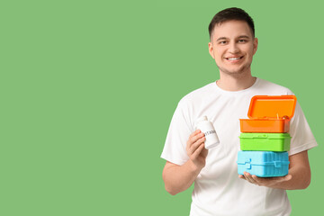 Wall Mural - Handsome young man with vitamins and portion control containers on green background. Healthy food concept