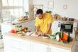 © Pixel-Shot - Handsome young man with fresh vegetables and notebook planning his diet in kitchen. Healthy food concept