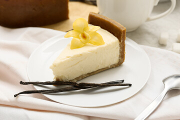 Wall Mural - Plate of sweet cheesecake with vanilla flower and sticks on white background