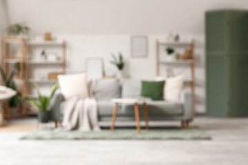 Wall Mural - Blurred view of light living room with sofa, shelf units and green plants