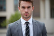 © He - Close up of man in grey suit looking at camera outdoors
