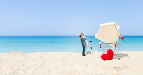 Wall Mural - Miniature couple with model house in shopping cart with space on tropical beach background, property and real estate business and investment concept, buy new home, hosue loan