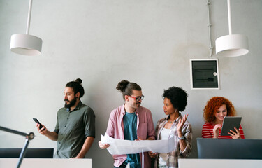 Canvas Print - Diverse group of happy employees analyzing reports with digital device, working together in office