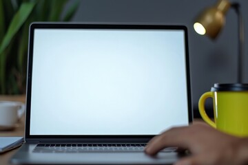 A man is at his desk in the office, using a laptop that currently displays nothing