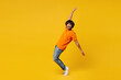 © ViDi Studio - Full body young cheerful Indian man wear orange t-shirt casual clothes standing on toes dancing lean back have fun spread hands looking camera isolated on plain yellow background. Lifestyle concept.