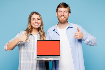 Wall Mural - Young couple two friends family IT man woman wearing shirt casual clothes together holding use work on laptop pc computer with blank screen area show thumb up isolated on plain blue background studio.