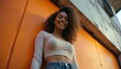 © vadosloginov - Smiling South Asian young adult poses confidently against vibrant urban backdrop during golden hour