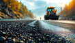 © abu - Workers and heavy equipment lay fresh asphalt on a gravel road in a dynamic construction scene.