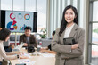 © PhugunStock - Asian businesswoman standing with arms crossed looking at camera, business people brainstorming, discussing analysis, innovation, collaboration. online business Sales techniques and strategic planning
