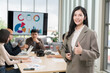 © PhugunStock - Asian businesswoman standing with thumbs up looking at camera, businessman brainstorming, discussing analysis, innovation, collaboration online business Sales techniques and strategic planning