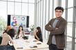 © PhugunStock - Asian male businessman standing with arms crossed looking at camera, businessman brainstorming, discussing analysis, innovation, collaboration online business Sales techniques and strategic planning